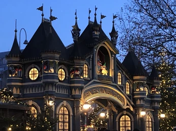 IMG_0581.jpeg Ein Weihnachtsmarkt mit beleuchteten Adventständen und geschmückter Fassade in der Dämmerung.A Christmas market with illuminated Advent stalls and a decorated façade at dusk.