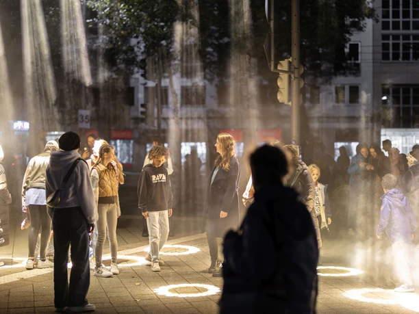 Menschen im Lichtkegel während des Lichtfests Leipzig zur Erinnerung an die Friedliche Revolution.
