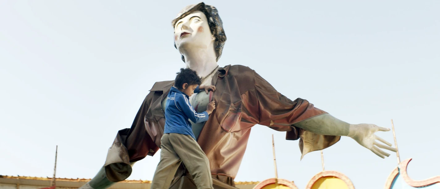 Ein Kind erklimmt eine Statue in überdimensionaler Menschengestalt.