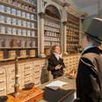 WirRheinlaender_Ausstellung (c) LVR-Freilichtmuseum Kommern.jpg Historische Apotheke mit traditionellen Apothekerschränken und Gefäßen. Eine Wachsfigur steht im historischen Kostüm vor der Theke und eine dahinter.