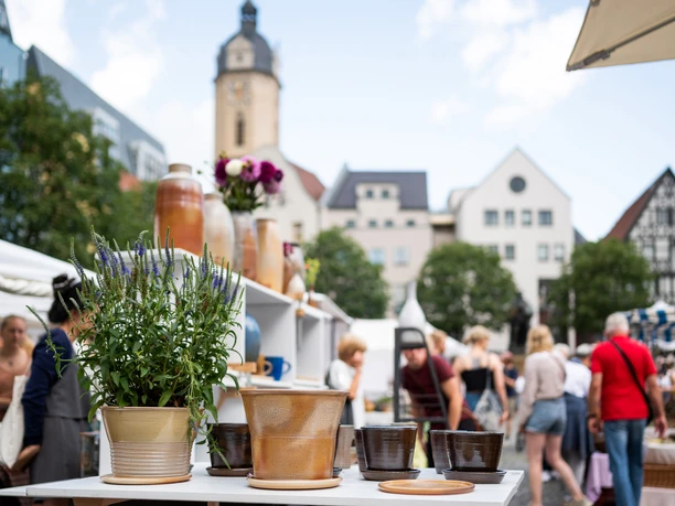 JenaerTöpfermarkt©JenaKultur_CWorsch+(104).jpg Im Vordergrund stehen Töpferwaren des Jenaer Töpfermarktes und im Hintergrund bewegen sich viele Menschen.