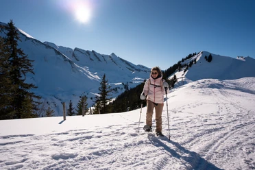 Eine Frau am Schneeschuhlaufen auf der Klewenalp bei Sonnenschein.