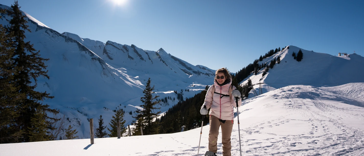 Eine Frau am Schneeschuhlaufen auf der Klewenalp bei Sonnenschein.