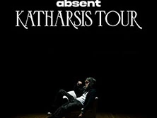 Zwei Personen sitzen auf einer Bühne in einem dunklen Raum, beleuchtet von einem einzelnen Scheinwerfer.