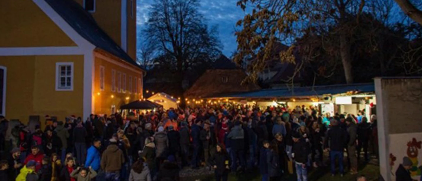 Adventsmarkt Thallwitz OT Nischwitz - Weihnachten in der Region Leipzig Menschen genießen den abendlichen Adventsmarkt vor der beleuchteten Kirche Nischwitz.