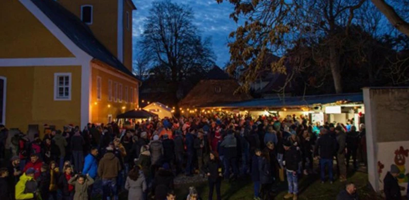 Adventsmarkt Thallwitz OT Nischwitz - Weihnachten in der Region Leipzig Menschen genießen den abendlichen Adventsmarkt vor der beleuchteten Kirche Nischwitz.