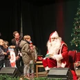 Schkeuditzer Weihnachtsmarkt - Weihnachten in der Region Leipzig Der Weihnachtsmann sitzt neben einem geschmückten Baum und übergibt den Kindern Geschenke.