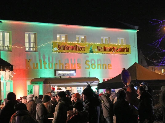 Kulturhaus Schkeuditzer Weihnachtsmarkt -Weihnachten in der Region Leipzig Vor dem beleuchteten Kulturhaus auf dem Schkeuditzer Weihnachtsmarkt tummeln sich zahlreiche Besucher.