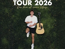 Ein junger Mann entspannt auf grünem Untergrund neben einer Akustikgitarre; Tour 2026-Poster.