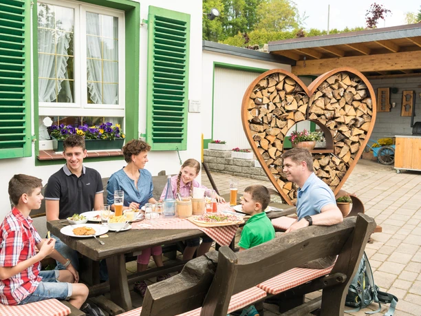Gemütliche Einkehr im Restaurant "Kleine Schweiz" in Velbert Eine Familie genießt ein Essen im Freien an einem rustikalen Holztisch.