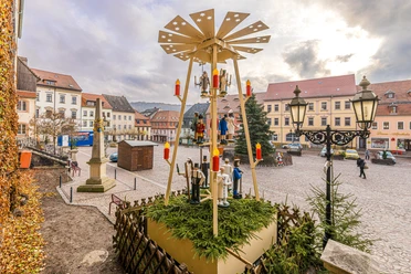 Marktplatz von Roßwein mit weihnachtlicher Pyramide, umgeben von historischen Gebäuden.