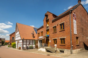 Nieheim-Sackmuseum-Teutoburger-Wald-Stadt-Nieheim-D-Ketz-205.jpg Backsteinbau des Sackmuseums in Nieheim mit Eingangstreppe und Fachwerkhaus daneben bei Sonnenschein.