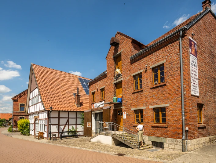 Nieheim-Sackmuseum-Teutoburger-Wald-Stadt-Nieheim-D-Ketz-205.jpg Backsteinbau des Sackmuseums in Nieheim mit Eingangstreppe und Fachwerkhaus daneben bei Sonnenschein.