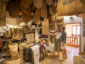 Nieheim-Sackmuseum-Teutoburger-Wald-Stadt-Nieheim-D-Ketz-212.jpg Paar betrachtet in einem Raum des Sackmuseums Nieheim alte Lein- und Jutesäcke an Wänden und Decke.