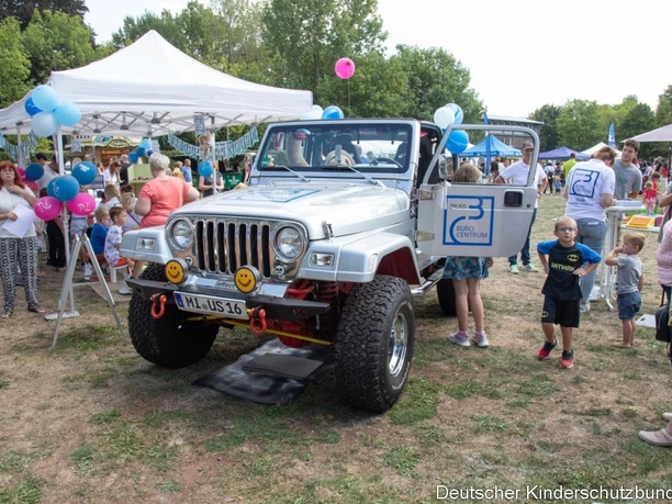 Eine Stadt für alle.jpg Auf dem Bild ist ein Auto mit vielen Kinder drumherum abgebildet