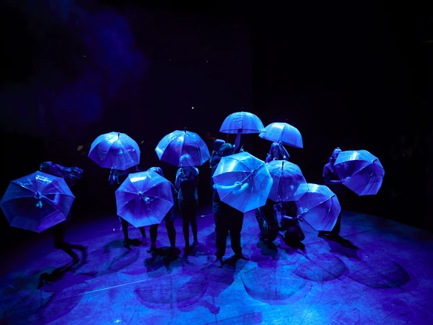 Community Dance.jpg Das Bild zeigt die Tänzer von Community Dance unter Regenschirmen