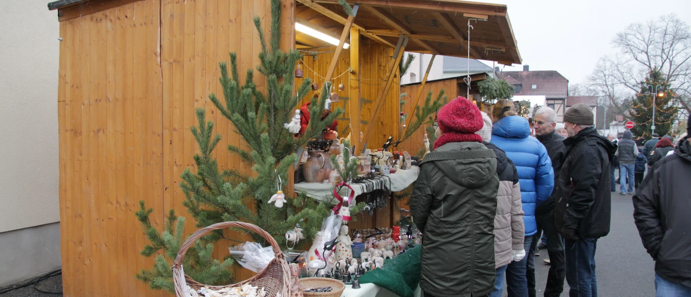 Weihnachtsmarkt Beucha - Weihnachten in der Region Leipzig Festlich geschmückter Weihnachtsmarktstand mit handgefertigten Waren, vor dem sich Besucher umschauen und stöbern