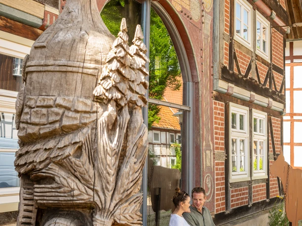 Nieheim-Deutsches-Kaesemuseum-Teutoburger-Wald-Stadt-Nieheim-D-Ketz-227.jpg Holzskulptur vor dem Deutschen Käsemuseum in Nieheim, Paar sitzt auf Bank am Fachwerkhaus.