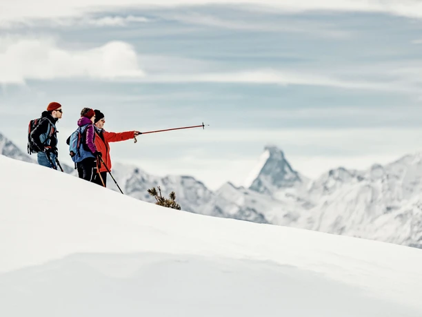 Randonnée guidée sur les crêtes avec pause pour admirer la vue Les participants à une randonnée en raquettes sur l'arête d'Aletsch s'attardent avec vue sur le Cervin et discutent de l'itinéraire sur l'arête hivernale.