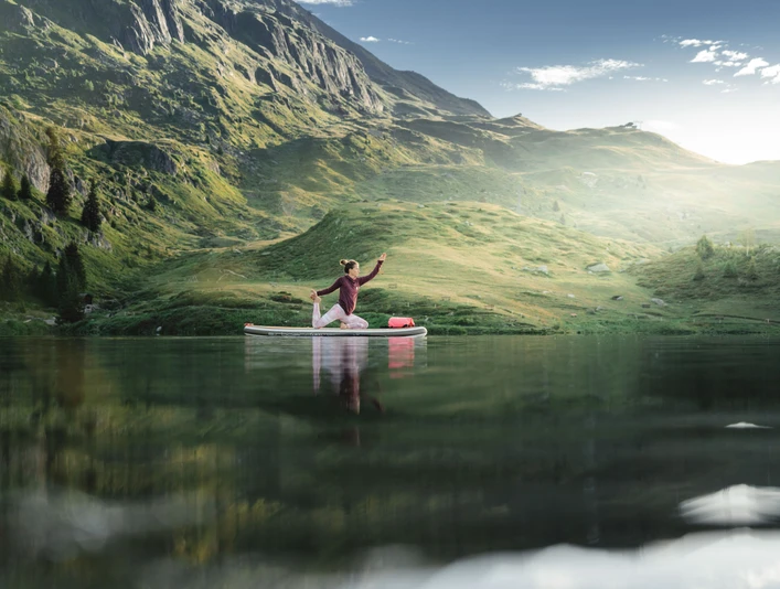 SUP Yoga auf dem Bettmersee Frau übt SUP Yoga Bettmersee im Sommer auf einem ruhigen Bergsee umgeben von grünen Hängen und alpiner LandschaftWoman practicing SUP Yoga Bettmersee in summer on a quiet mountain lake surrounded by green slopes and alpine sceneryUne femme pratique le SUP Yoga Bettmersee en été sur un lac de montagne tranquille entouré de pentes vertes et de paysages alpins.