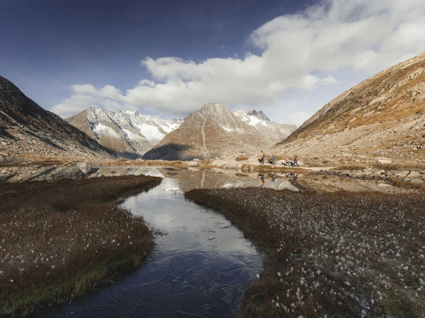 Mountain landscape with Lake Märjelen Participants on the Jungfraujoch Aletsch glacier tour hike along a glacial lake with a view of the surrounding peaks in autumn
