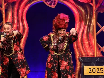 Röschen Sitzung in Cologne Zwei Personen stehen auf einer Bühne mit roten, floralen Kostümen vor einem kunstvoll gestalteten Hintergrund.Two people stand on a stage with red, floral costumes in front of an artistically designed background.