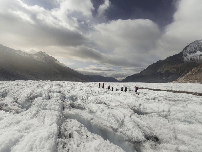 Groupe en route sur le glacier Teilnehmer der UNESCO Gletschertour Aletsch bewegen sich in Seilschaft über die weiten Eisfelder des AletschgletschersParticipants on the UNESCO Aletsch Glacier Tour move across the vast ice fields of the Aletsch Glacier in rope teamsLes participants au tour du glacier d'Aletsch de l'UNESCO se déplacent en cordée sur les vastes champs de glace du glacier d'Aletsch.