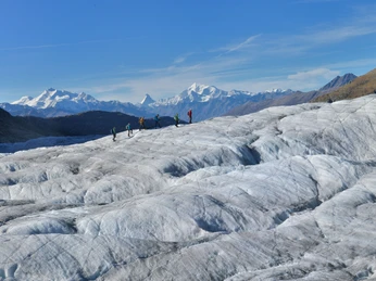 Geführte Tour auf dem Aletschgletscher Gruppe von Bergsteigern wandert bei Sonnenschein während der 2-Tage-Erlebnis Gletschertour Aletsch auf dem AletschgletscherGroup of mountaineers hiking on the Aletsch Glacier in the sunshine during the 2-day Aletsch Glacier Tour experienceGroupe d'alpinistes marchant sur le glacier d'Aletsch sous le soleil pendant les 2 jours de l'excursion "Gletschertour Aletsch".