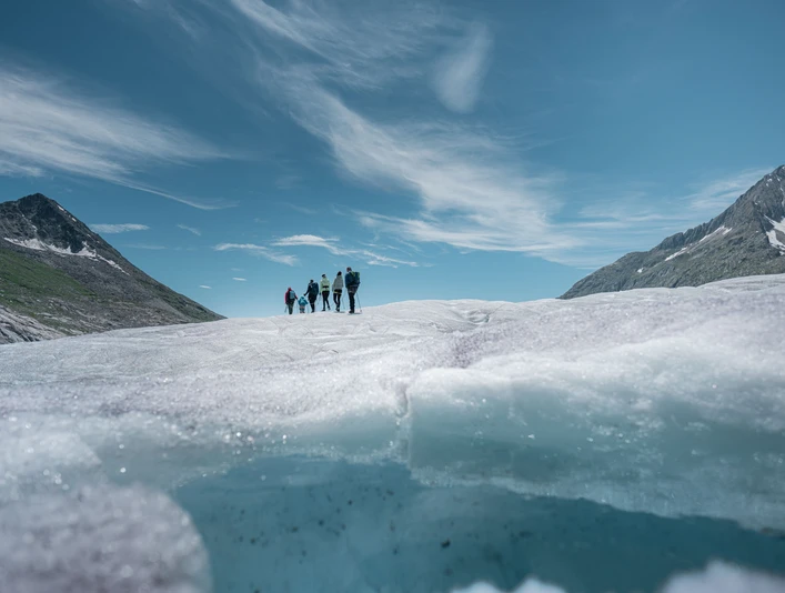 Hikers on the Aletsch Glacier in summer Gruppe von Wanderern überquert den Aletschgletscher an einem klaren Sommertag während der 2-Tage-Erlebnis Gletschertour AletschGroup of hikers cross the Aletsch Glacier on a clear summer day during the 2-day Aletsch Glacier Tour experienceGroupe de randonneurs traversant le glacier d'Aletsch par une claire journée d'été lors du tour du glacier d'Aletsch de 2 jours.