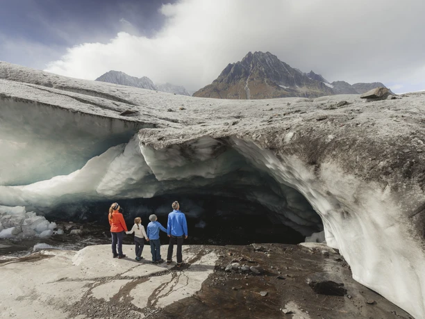 Une famille découvre une grotte de glace sur le glacier d'Aletsch Famille devant une grotte de glace sur le glacier d'Aletsch pendant le tour du glacier Jungfraujoch Märjelensee