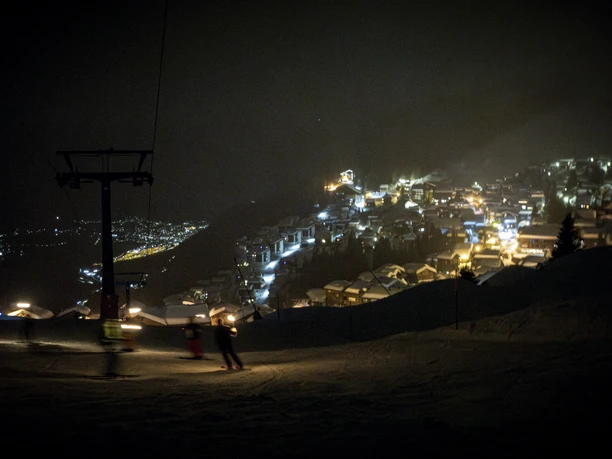 Descente aux flambeaux avec vue sur Bettmeralp Les skieurs descendent dans la vallée de nuit avec des torches pendant le dîner au clair de lune Aletsch Arena près de Bettmeralp