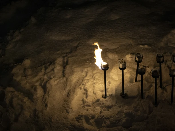 Fackeln bei Nacht im Schnee Brennende Fackeln im Schnee leuchten während des Mondscheinessen Aletsch Arena bei der Bettmeralp