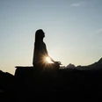Yoga-Silhouette im Abendlicht Frau meditiert im Lotussitz auf einem Felsen beim Sonnenuntergang Yoga Aletsch Arena mit Blick auf die BergeWoman meditating in the lotus position on a rock at sunset Yoga Aletsch Arena with a view of the mountainsFemme méditant en position du lotus sur un rocher au coucher du soleil Yoga Aletsch Arena avec vue sur les montagnes