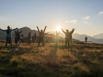 Yoga group at sunset on the Bettmeralp Gruppe von Menschen hebt die Arme im goldenen Licht beim Sonnenuntergang Yoga Aletsch Arena auf der BettmeralpGroup of people raising their arms in the golden light at sunset Yoga Aletsch Arena on BettmeralpGroupe de personnes levant les bras dans la lumière dorée au coucher du soleil Yoga Aletsch Arena sur la Bettmeralp