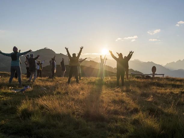 Yoga group at sunset on the Bettmeralp Group of people raising their arms in the golden light at sunset Yoga Aletsch Arena on Bettmeralp