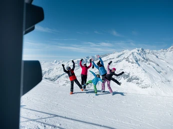 Gruppenfoto Skiline mit Alpenpanorama Gruppe springt in die Luft vor verschneiten Gipfeln beim Fotopoint während der Glacier Challenge Skiline Aletsch ArenaGroup jumps into the air in front of snow-covered peaks at the photo point during the Glacier Challenge Skiline Aletsch ArenaGroupe sautant en l'air devant des sommets enneigés au point photo pendant le Glacier Challenge Skiline Aletsch Arena