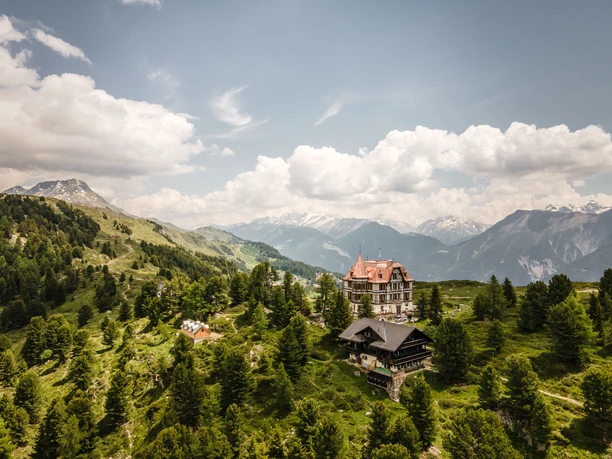 Luftaufnahme Villa Cassel inmitten der Berge Kräuterwanderung Aletsch Arena mit Panorama auf die Villa Cassel, eingebettet in die Bergwelt und den Aletschwald