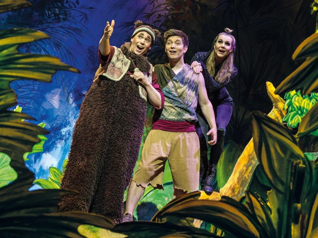 Dschungelbuch - das Musical.jpg >Das Bild zeigt ein Bühnenbild aus dem Musical Dschungelbuch. Es zeigt Mogli, Balu und ein Mädchen