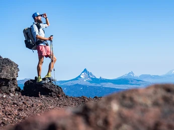 Zu Fuß durch Neuseeland Ein Wanderer im Gebirge hebt seine Hand gegen die Sonne, blickt weit in die Ferne.A hiker in the mountains raises his hand against the sun, gazing far into the distance.