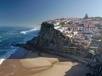 Portugal & Madeira Ein Küstenort an einer Klippe mit weißen Häusern, der über einem Strand mit sanften Wellen thront.A coastal village on a cliff with white houses perched above a beach with gentle waves.