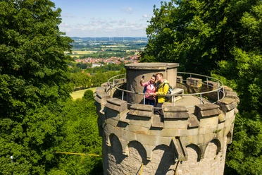 Teutoburger-Wald-Stadt-Nieheim-D-Ketz-124.jpg Zwei Wanderer machen ein Selfie auf einem historischen Turm mit Blick auf Nieheim und Landschaft.