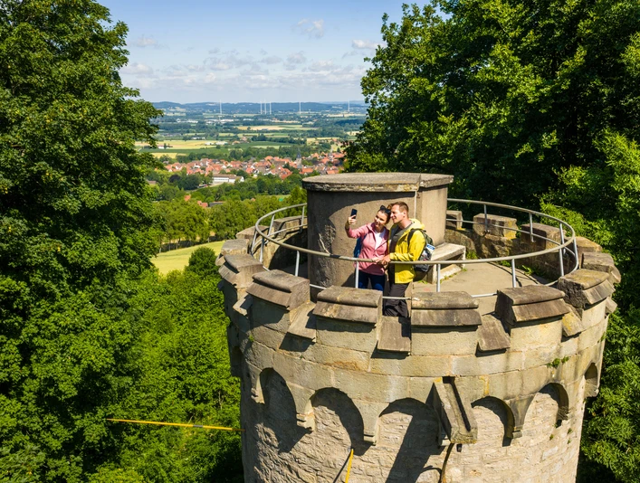Teutoburger-Wald-Stadt-Nieheim-D-Ketz-124.jpg Zwei Wanderer machen ein Selfie auf einem historischen Turm mit Blick auf Nieheim und Landschaft.