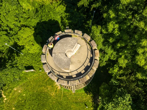 Teutoburger-Wald-Stadt-Nieheim-D-Ketz-126.jpg Runder Aussichtsturm in Nieheim von oben, umgeben von dichtem Wald mit zwei Besuchern auf der Plattform.