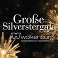 Stimmungsvolle Silvestergala im Festsaal der Wolkenburg mit funkelndem Feuerwerk im Hintergrund.