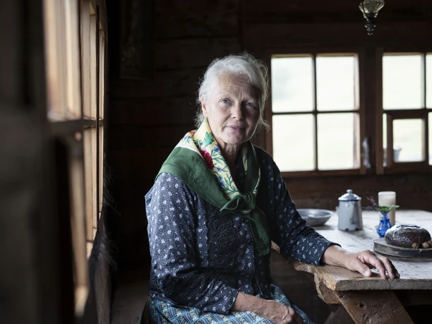Témoin de la tradition alpine au musée de l'alpage Schaubuttern Alpmuseum Aletsch avec une femme en habits traditionnels à la table en bois dans le chalet d'alpage