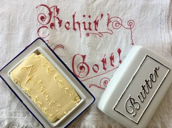 Butter with embossing in the Riederalp Alpine Museum Schaubuttern Alpmuseum Aletsch mit frisch geformter Butter in traditioneller Holzform auf besticktem LeinentuchAletsch Alpine Museum show churn with freshly churned butter in a traditional wooden mold on embroidered linen clothHuîtres de présentation du musée d'alpage d'Aletsch avec du beurre fraîchement moulé dans un moule en bois traditionnel sur une toile de lin brodée