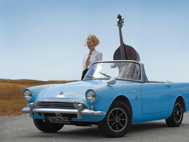 12th Multiphonics Festival 2025, Gina Schwarz Gina Schwarz next to a blue vintage convertible and an upright double bass.