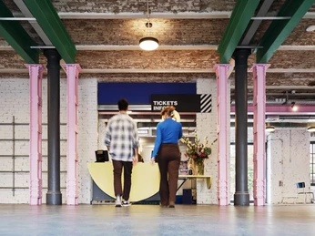 Schirn Dondorf Druckerei Foyer mit Tickets/Info, rosa Säulen, zwei Besucher*innen im VorbeigehenLobby with tickets/info, pink columns, two visitors walking past