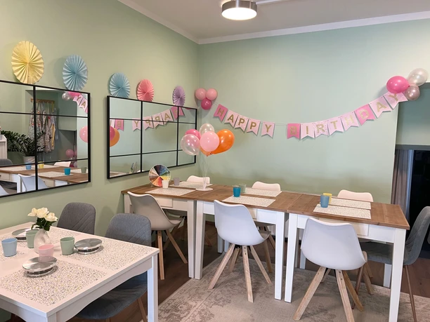 Lieblingstasse-innen.jpg Liebevoll dekorierter Raum mit Maltischen und Geburtstagsgirlande an der Wand