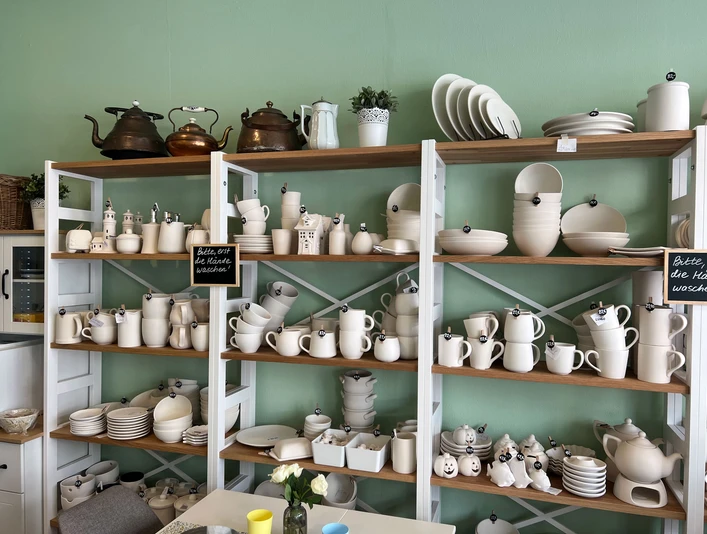 Lieblingstasse-Rohkeramik.jpg Regale mit verschiedenen Keramikwaren, darunter Kannen und Tassen